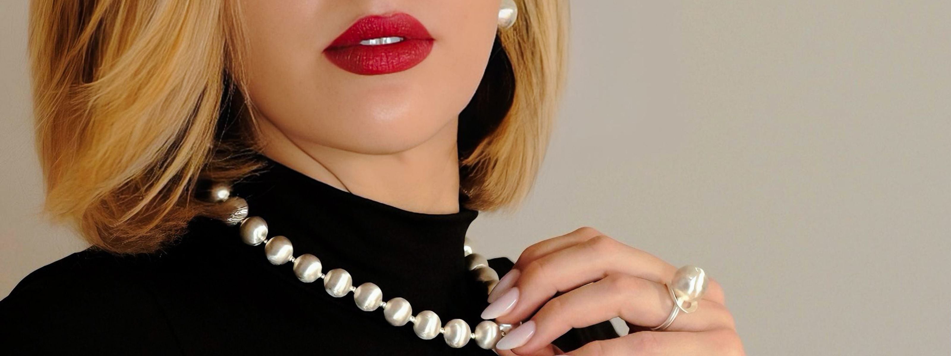 Silberne Schmuckkollektion mit Halsketten, Armbändern, Ringen und Ohrringen mit Kugeldetails auf weissem Hintergrund.