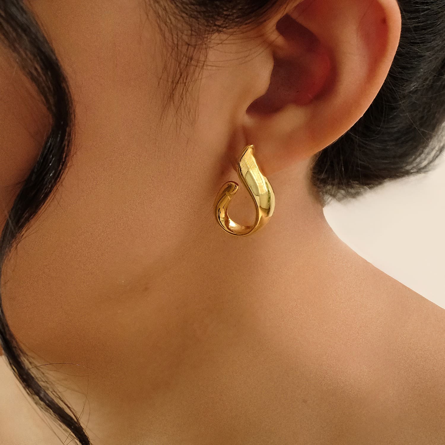 Detailaufnahme eines stilvollen goldenen Ohrsteckers von Cosytas, getragen am Ohr vor einem neutralen Hintergrund. Elegantes und zeitloses Design im Fokus.