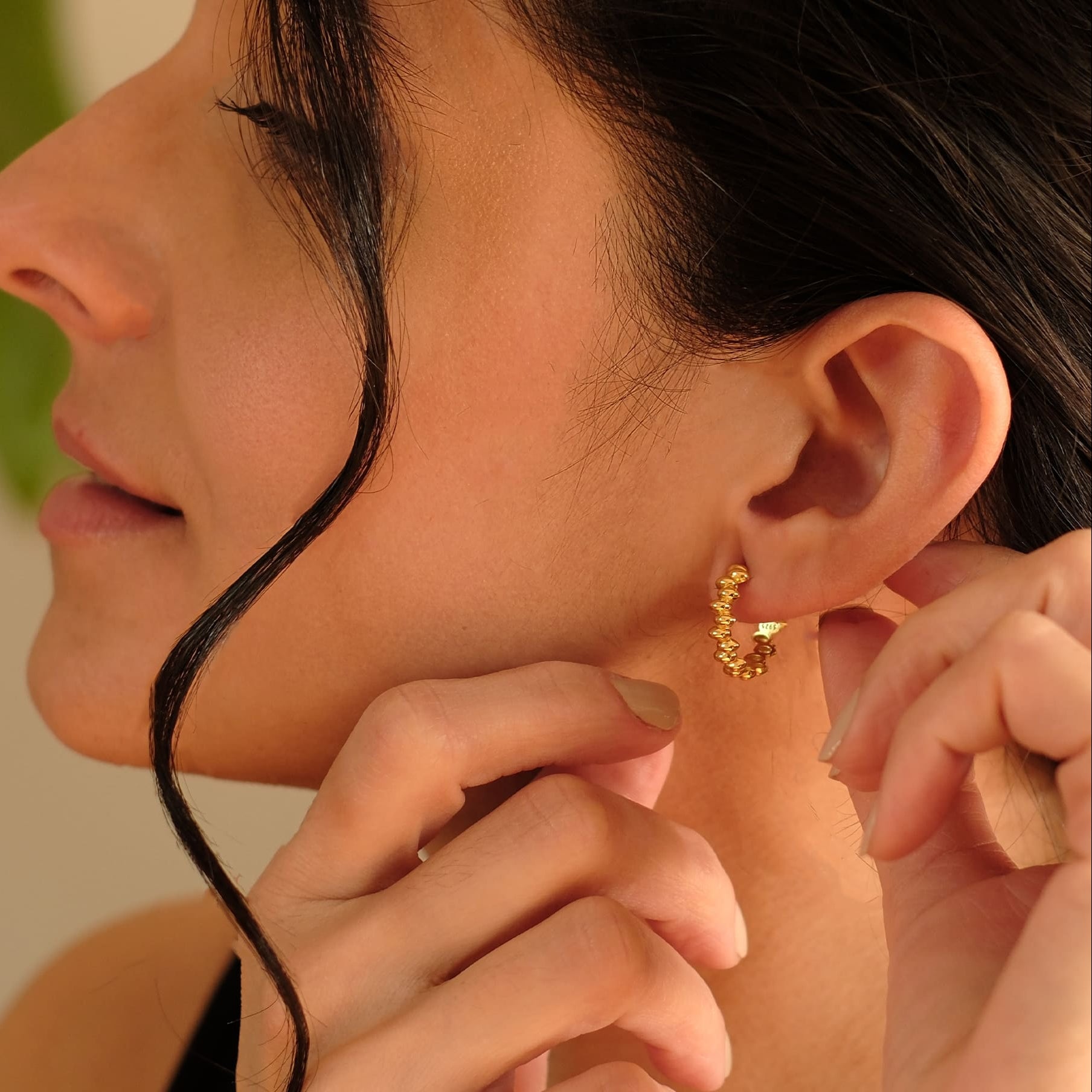 Nahaufnahme einer Frau mit den Cosytas Golden Bead Hoops, goldenen Creolen mit strukturierten Kugeldetails