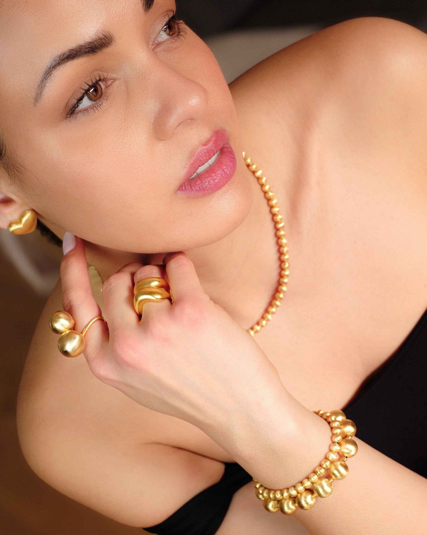 Frau trägt goldenes Schmuck-Set von Cosytas – Halskette, Ring und Armband aus 18k vergoldetem Gold