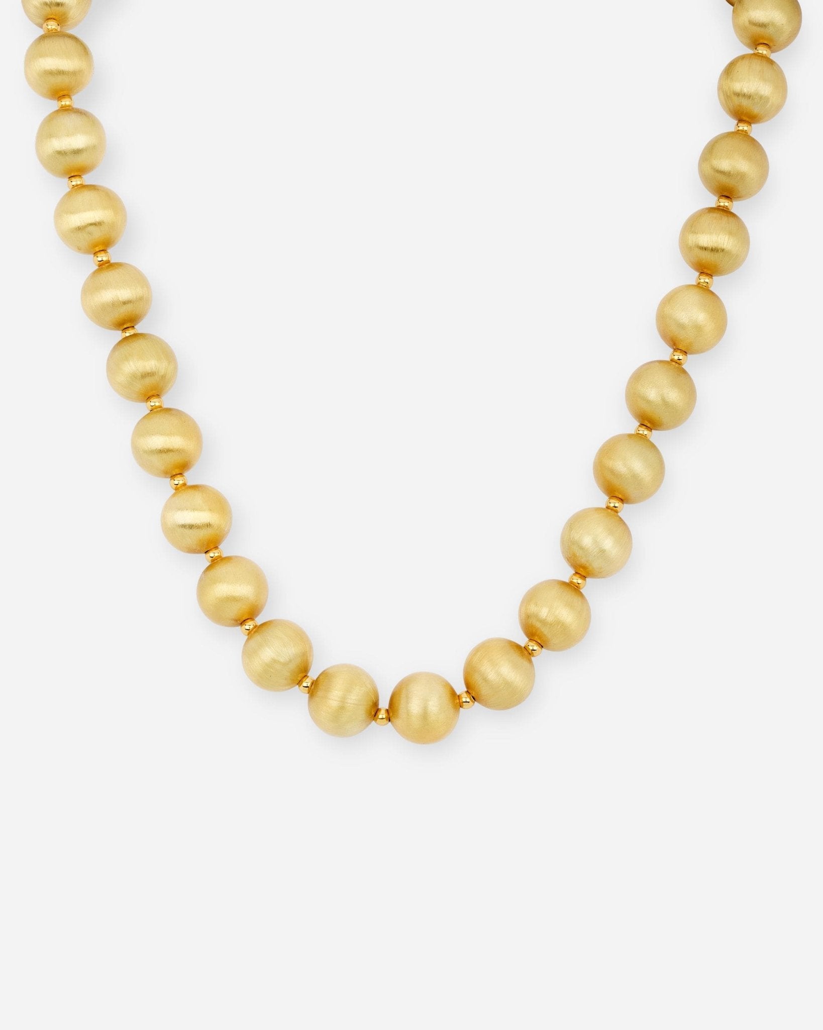 Lumina Gold Sphere Halskette mit mattierten, 18k vergoldeten Kugeln auf hellem Hintergrund.