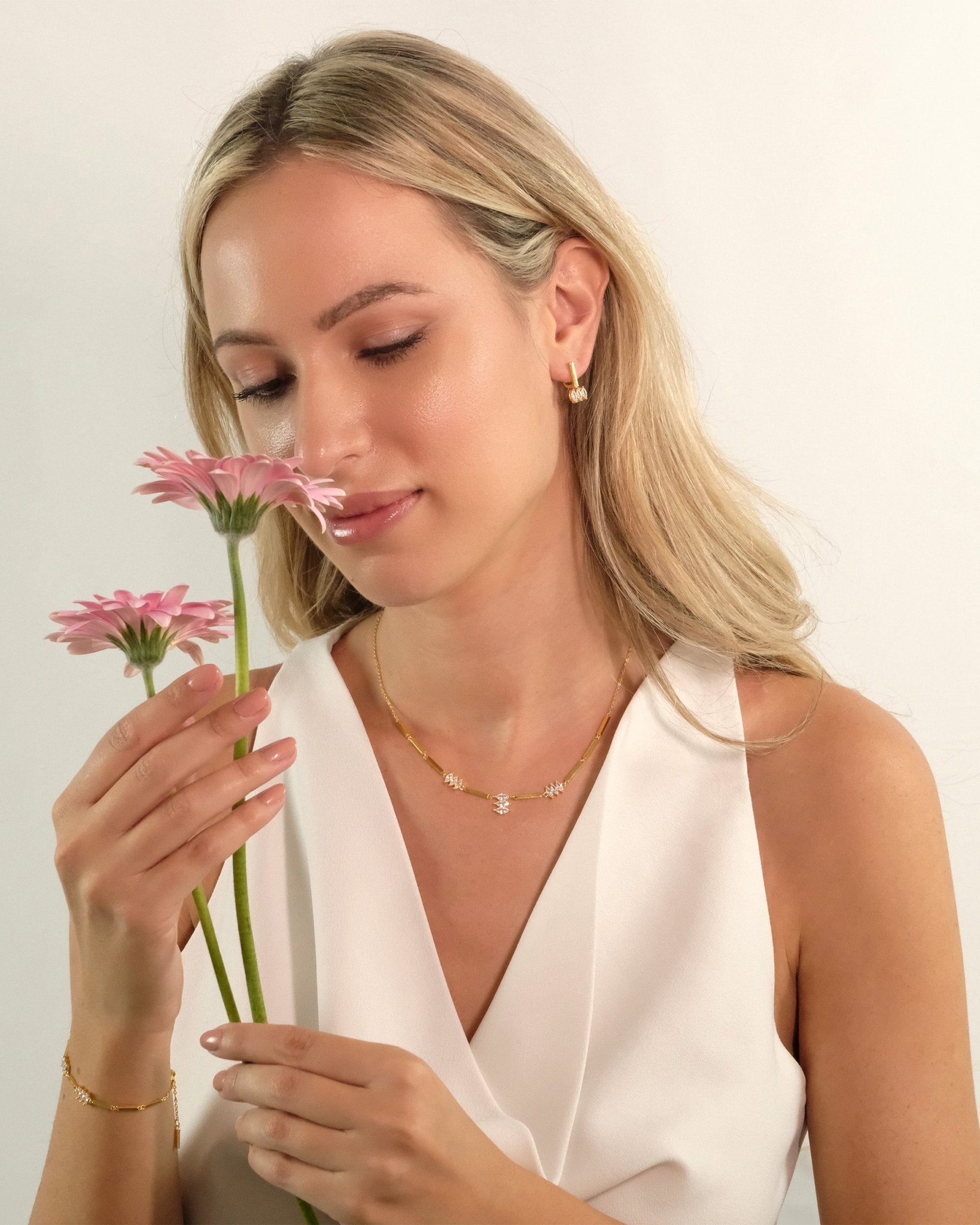 Model hält Blume und trägt Cosytas Moira White Ohrringe aus 18k Gold Vermeil auf 925 Silber mit weissen Zirkonia.