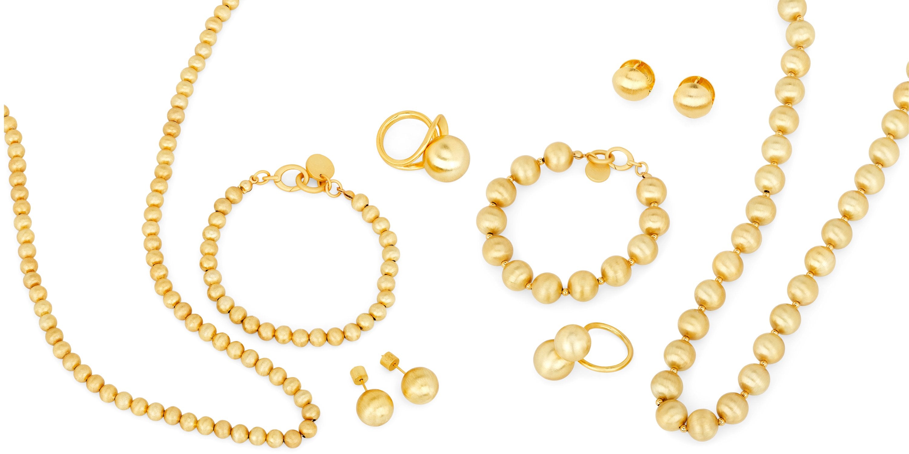 Flach gelegte Schmuckkollektion in Gold bestehend aus Halsketten, Armbändern, Ringen und Ohrringen mit Kugel- und Perlendetails, elegant arrangiert auf weissem Hintergrund.