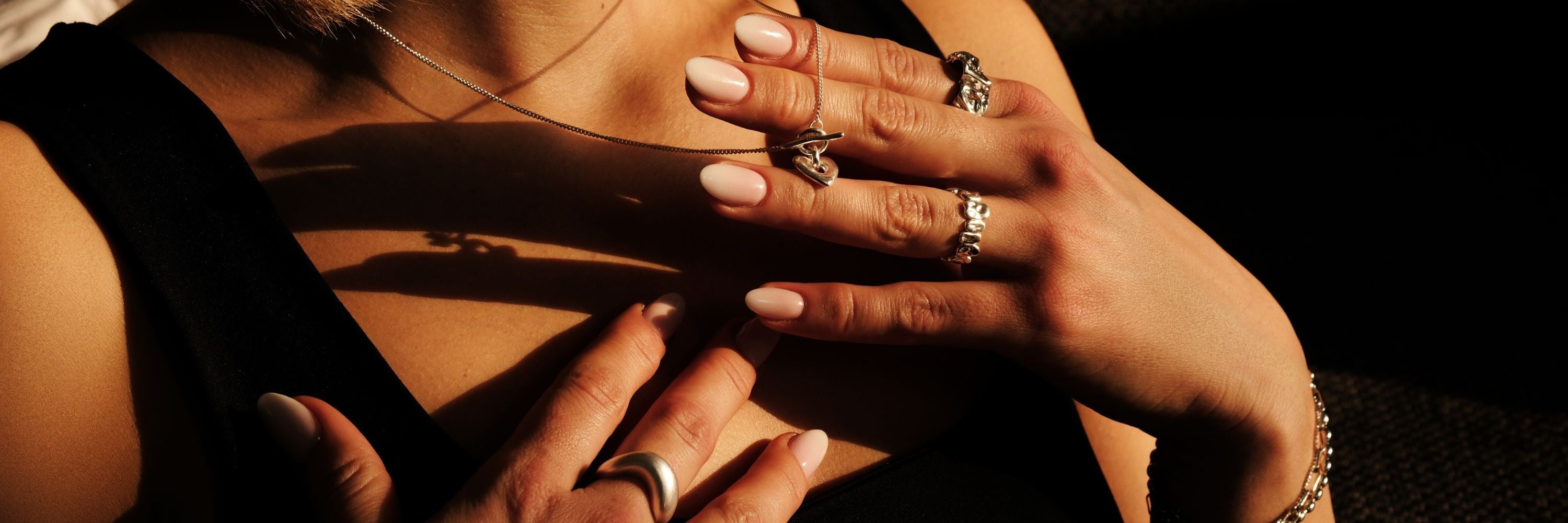 Hände mit eleganten Ringen, die im warmen Licht schimmern. Das Bild strahlt Raffinesse und zeitlose Eleganz aus, passend zur Cosytas-Schmuckkollektion.