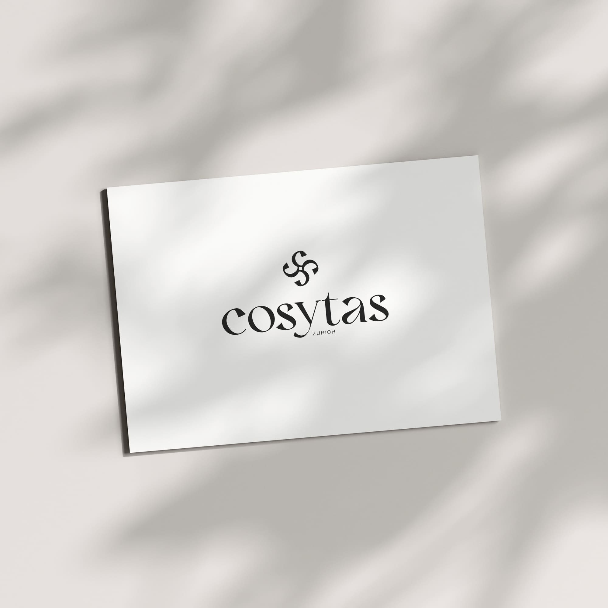 cosytas E-Gutschein mit elegantem Logo auf weissem Hintergrund. Sanfte Schatten und Sonnenlichteffekte sorgen für eine edle, minimalistische Optik.