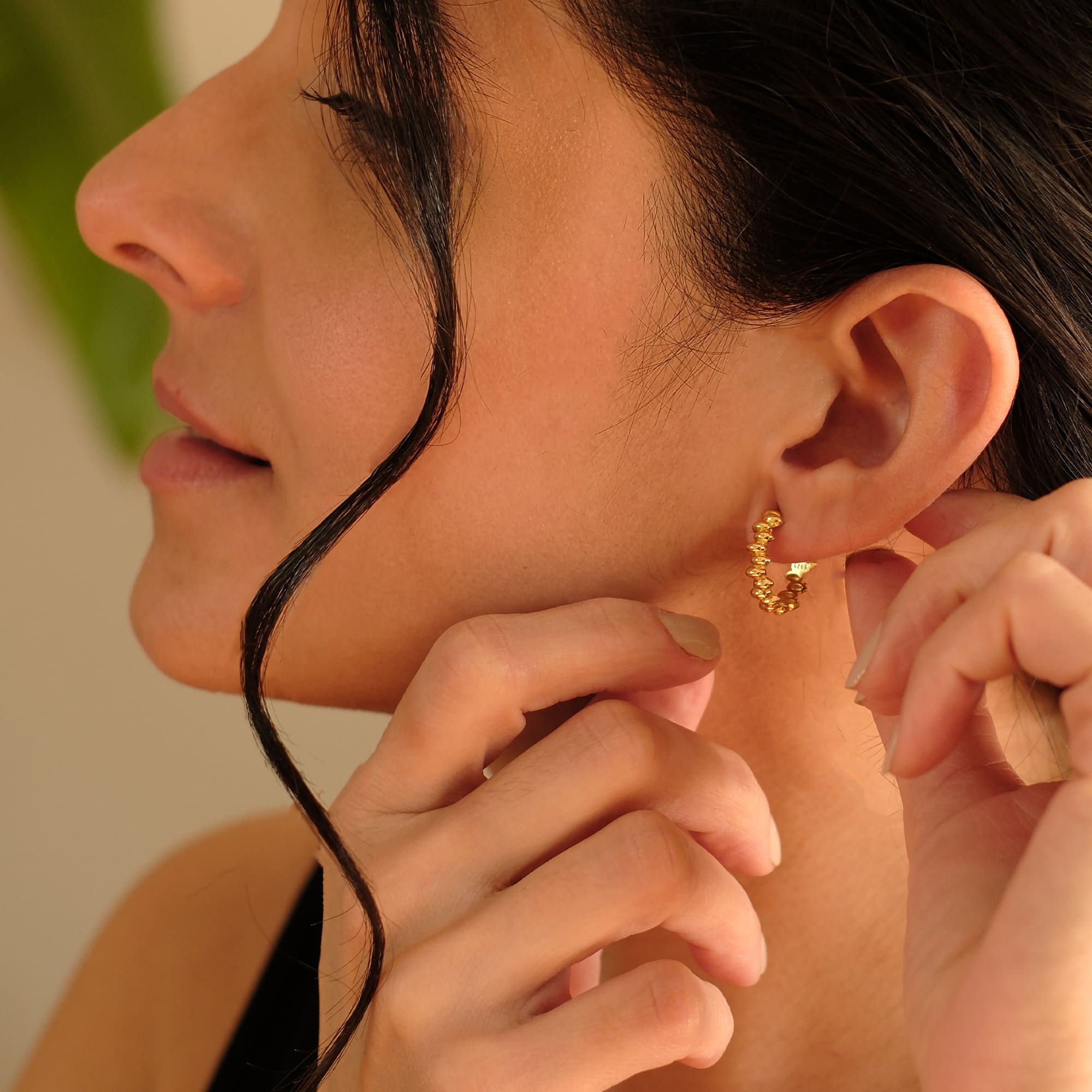 Nahaufnahme einer Frau mit den Cosytas Golden Bead Hoops. Die goldenen Creolen mit strukturierten Kugeldetails verleihen dem Look eine raffinierte Eleganz.