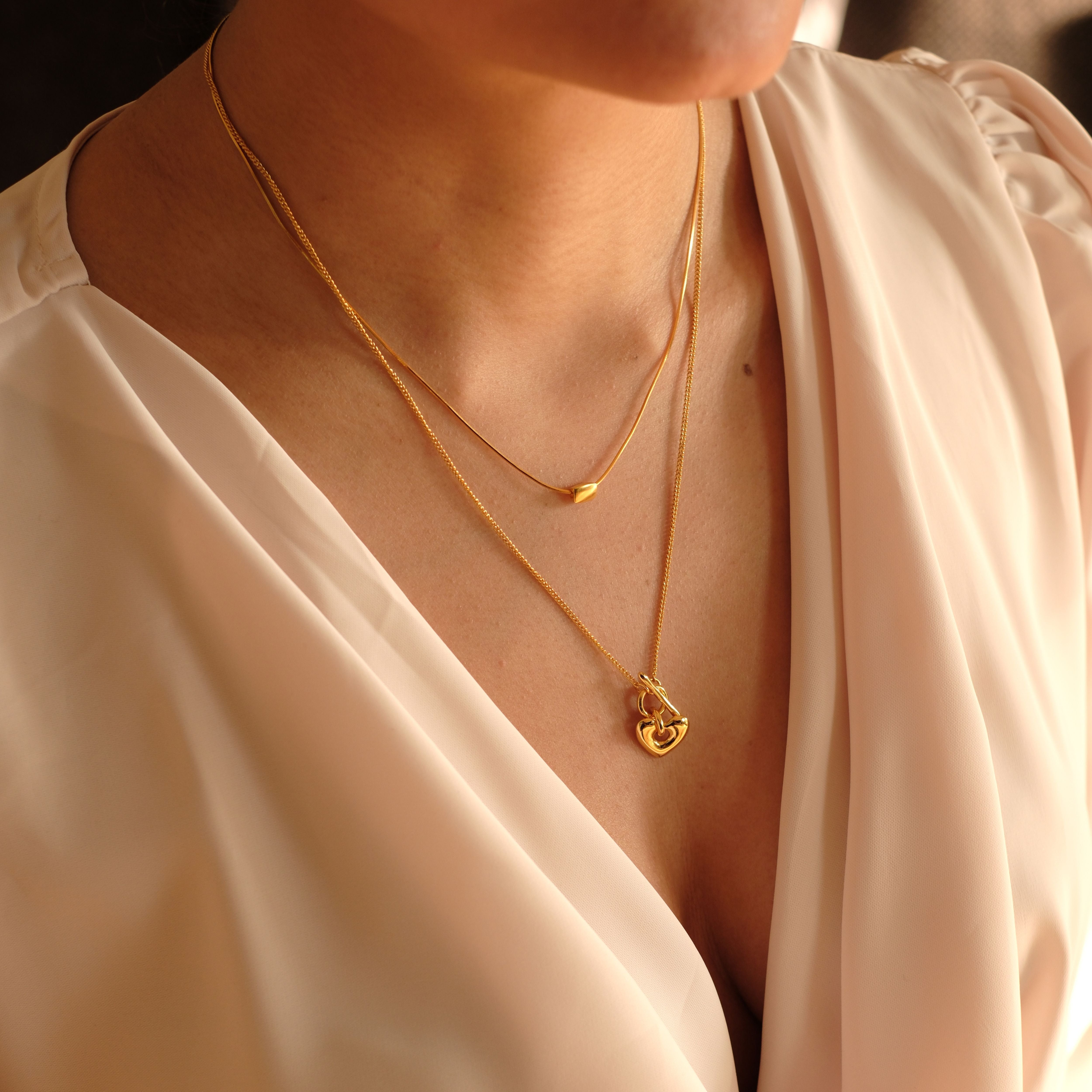 Cosytas goldene Layering-Halsketten mit zarten Anhängern in Herzform und minimalistischen Details, veredelt mit 18k Gold. Perfekte Schmuckkombination für einen femininen und stilvollen Look.