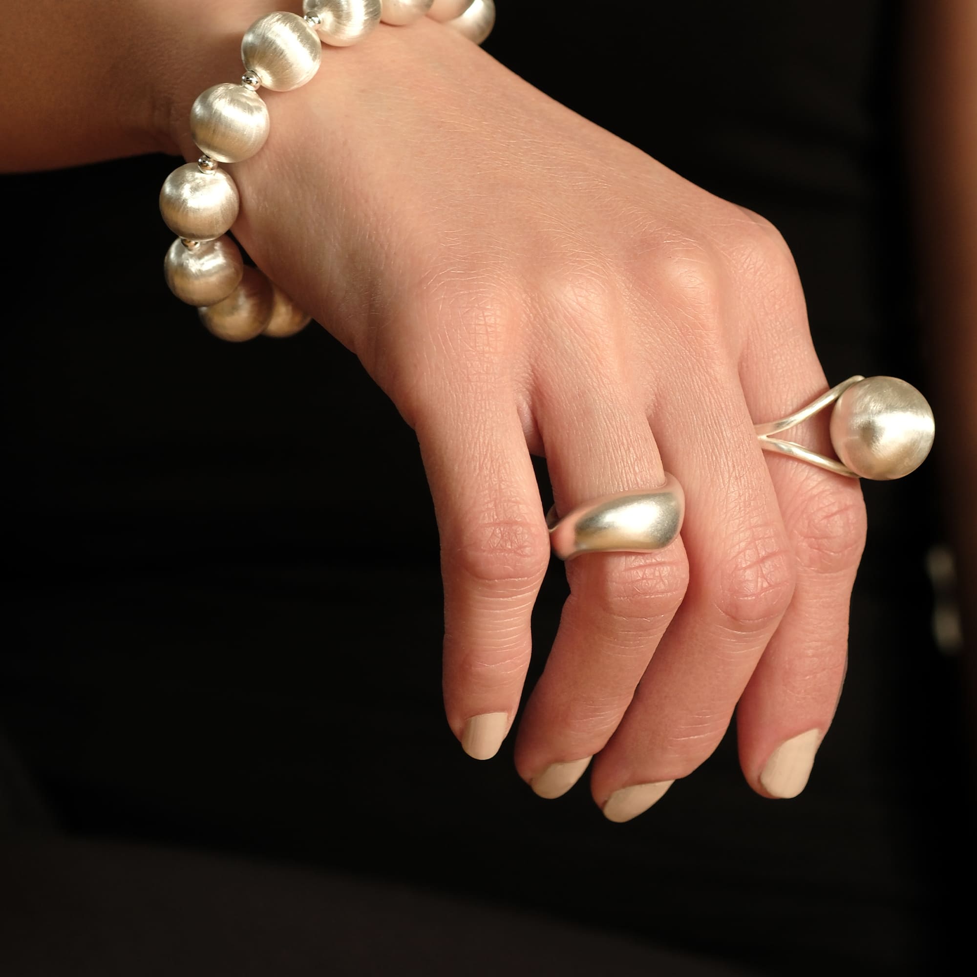 Model trägt den Cosytas Lumina Single Sphere Silberring. Offenes Design mit einer glänzenden Silberkugel, kombiniert mit passendem Armband für einen modernen und eleganten Look.