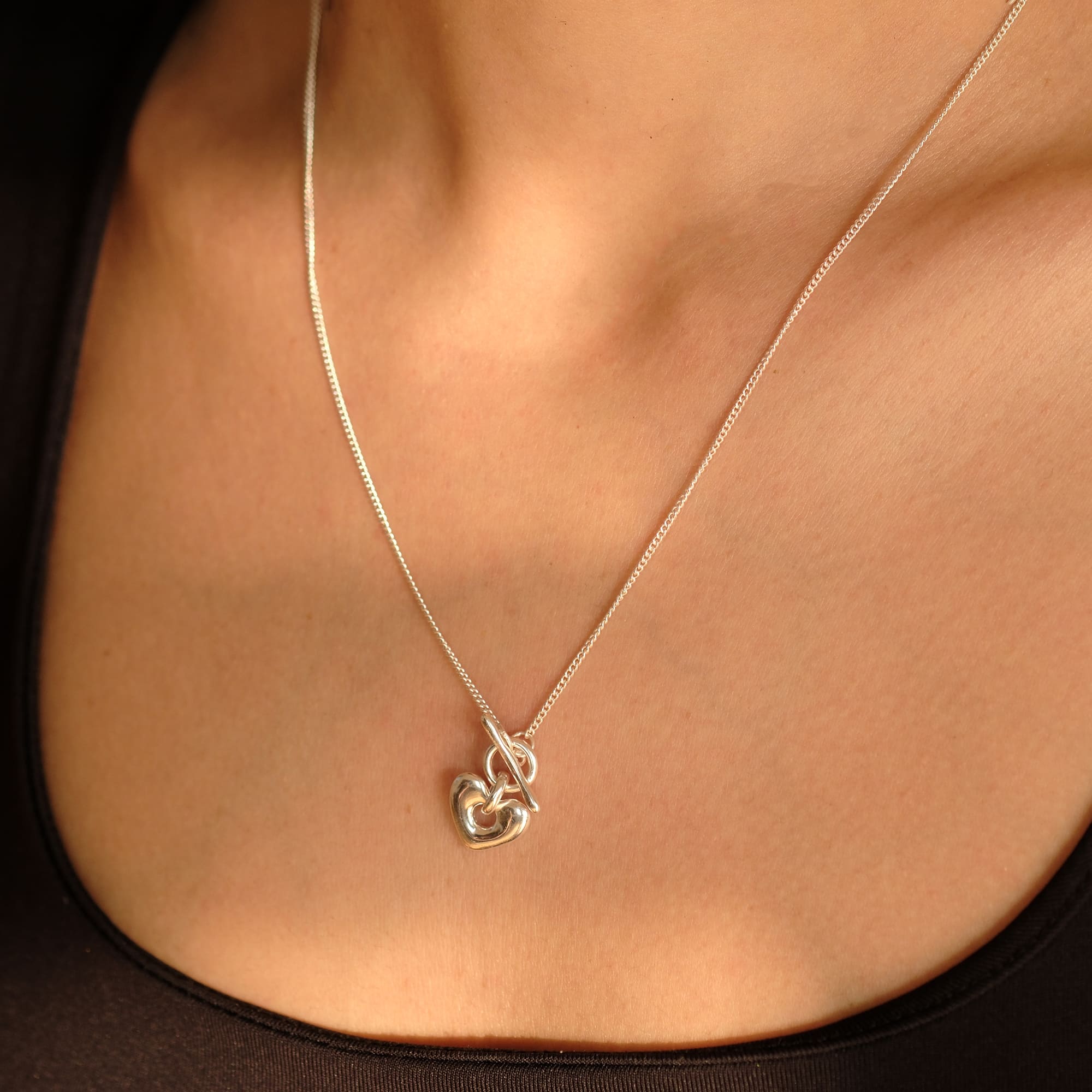 Model trägt die Cosytas Silver Heartbeat Halskette. Feine Silberkette mit elegantem, geschwungenem Herzanhänger. Ein symbolträchtiges Design für zeitlose Eleganz und emotionale Verbundenheit.