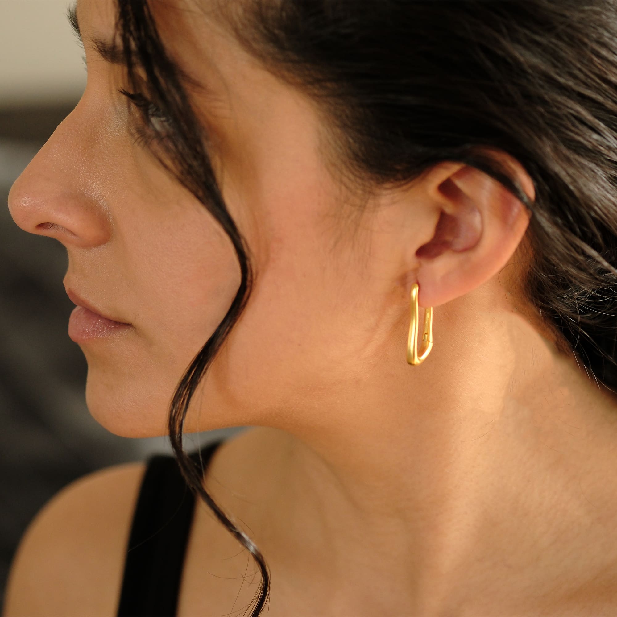 Seitliche Nahaufnahme einer Frau mit dem Cosytas Goldflow Ohrring aus Silber 925