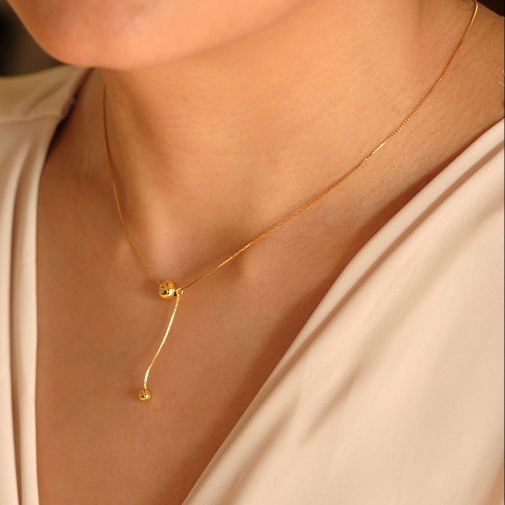 Model trägt die Cosytas Golden Balance Halskette im Y-Design mit zwei polierten Kugeln