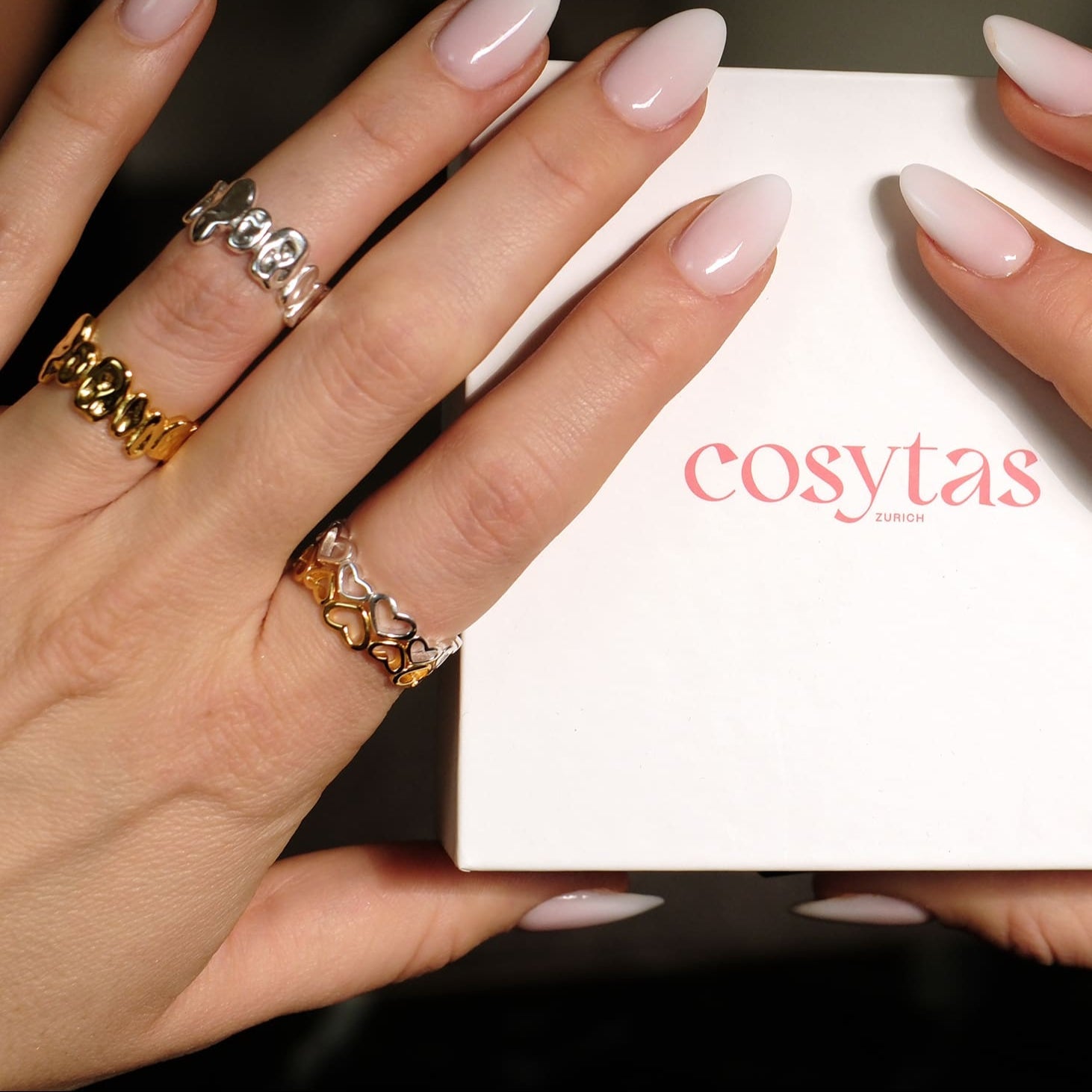 Hände Cosytas Heartbeat Ring, der mit seinem filigranen Herzdesign moderne Eleganz verkörpert