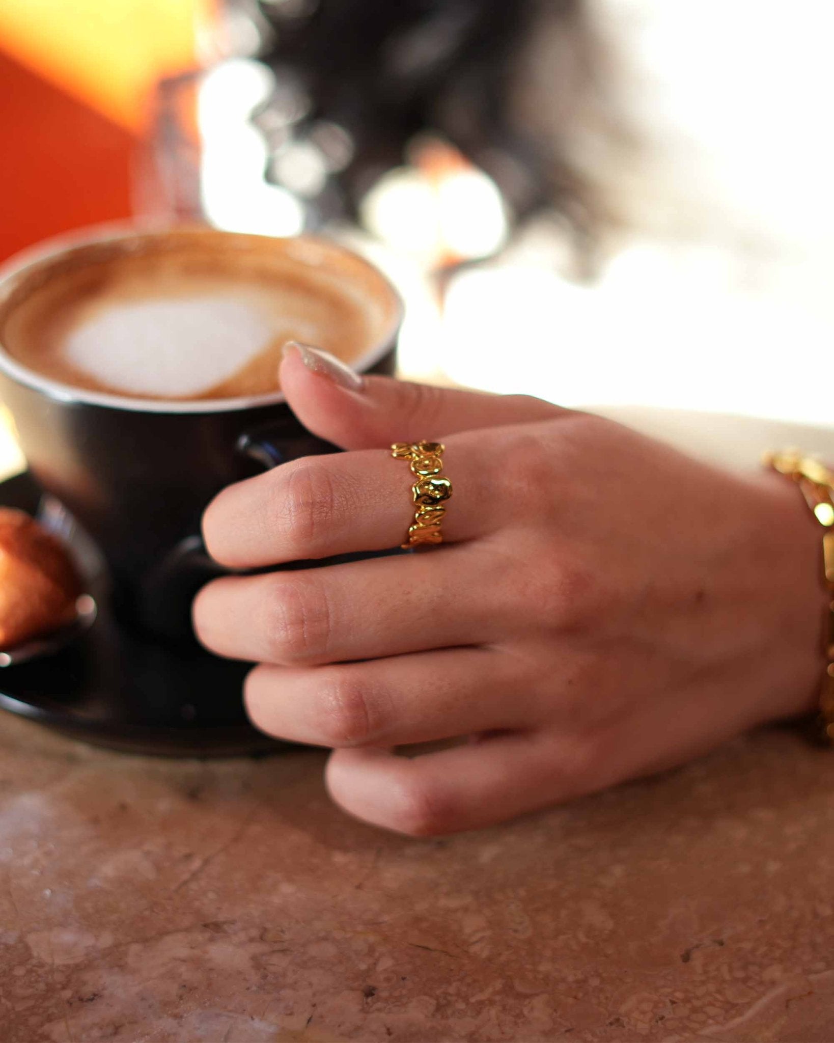 Frau trägt den Golden Pebble Ring beim Halten einer Kaffeetasse – 18K vergoldeter Schmuck