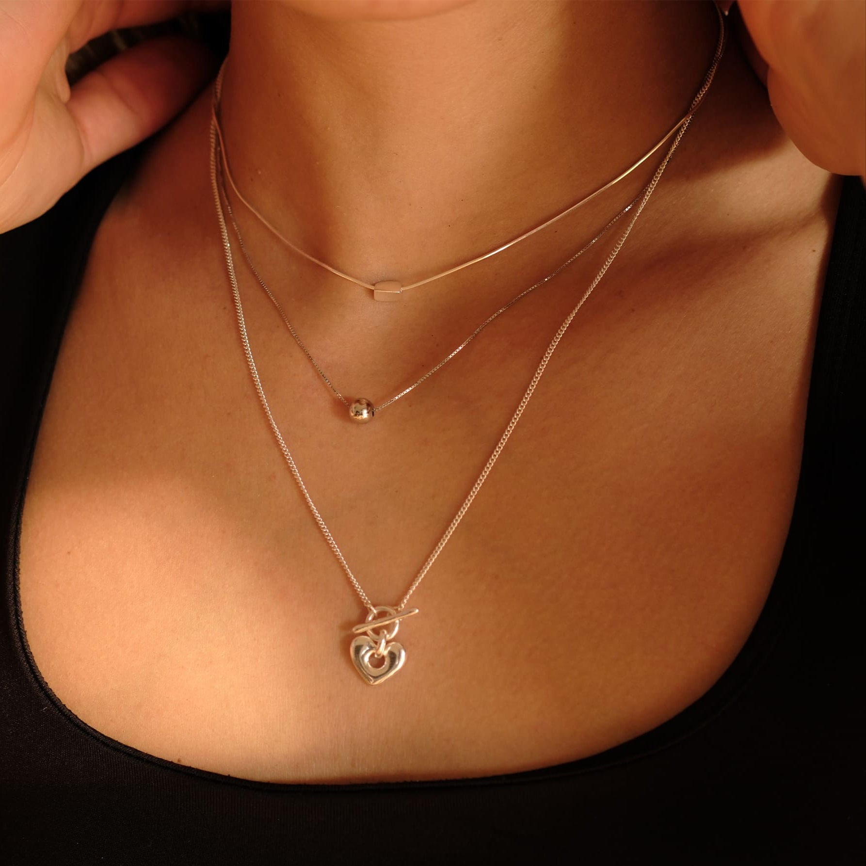 Model trägt die Cosytas Silver Heartbeat Halskette im Layering-Stil mit zwei weiteren feinen Silberketten