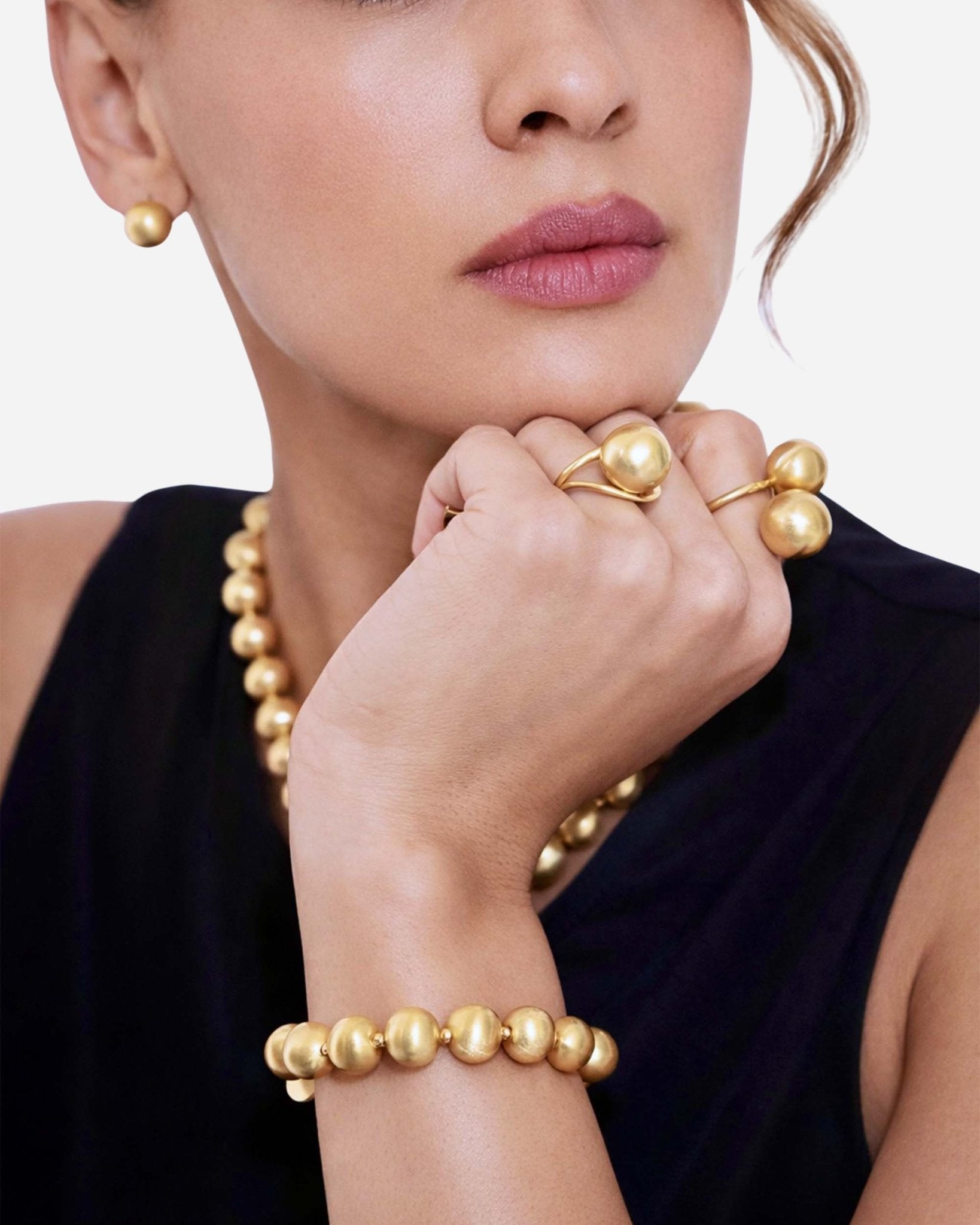 Modell trägt das Lumina Gold Sphere Armband mit gebürsteten Goldkugeln am Handgelenk.