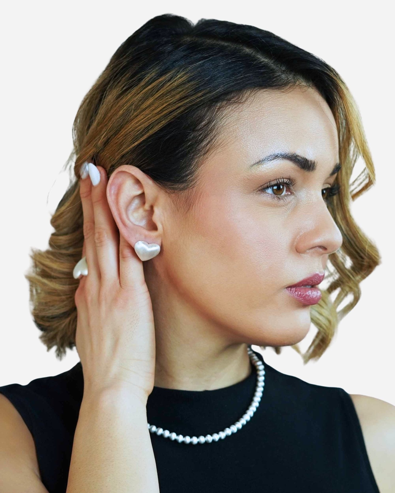 Model mit Cosytas Lumina Slim Silver Sphere Halskette, Armband und herzförmigen Ohrringen in Silber