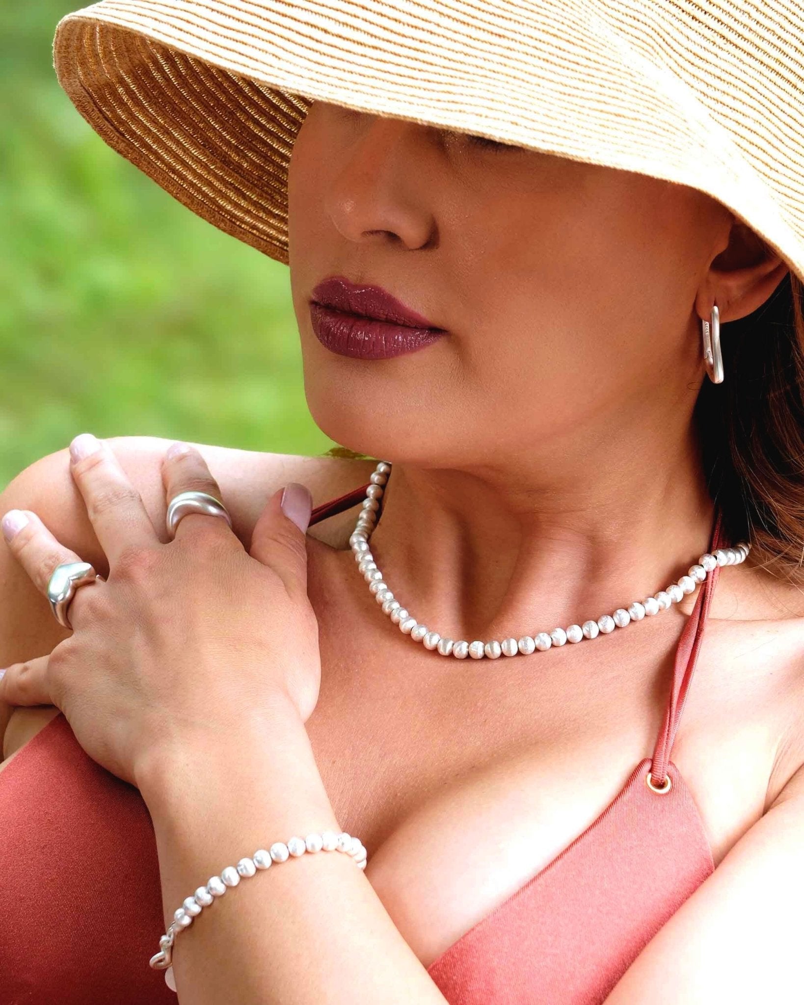 Modell trägt die Lumina Slim Silver Sphere Halskette und das passende Armband mit fein abgestuften, mattierten Silberkugeln.